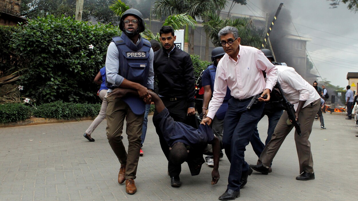 Des sauveteurs et des journalistes évacuent un homme blessé des lieux où des explosions et des coups de feu ont été entendus à l'hôtel Dusit, à Nairobi.