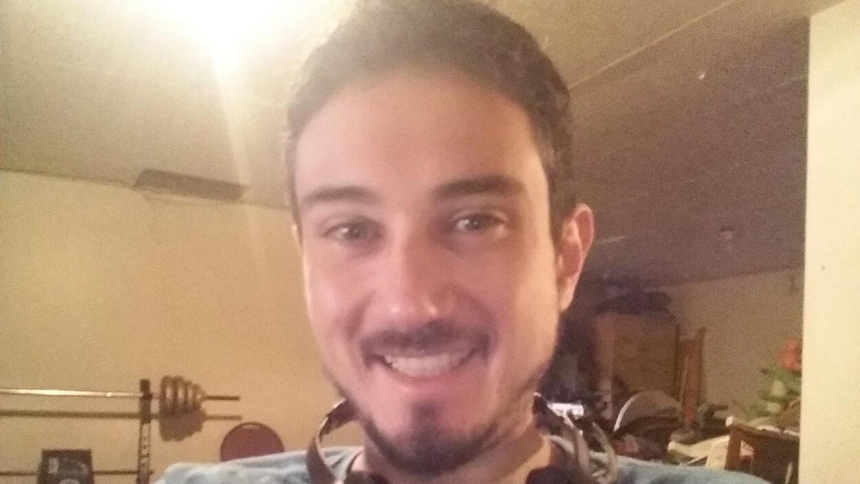 Un homme se prend en photo avec la caméra de son ordinateur, souriant.