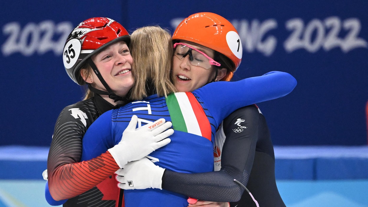 Trois patineuses se donnent une accolade.