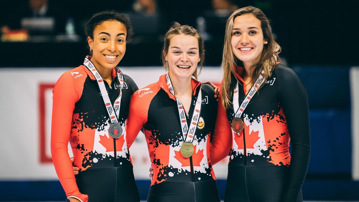 Kim Boutin sur la plus haute marche du podium avec une médaille d'or au cou. À côté d'elle, deux autres athlètes avec des médailles d'argent et de bronze.