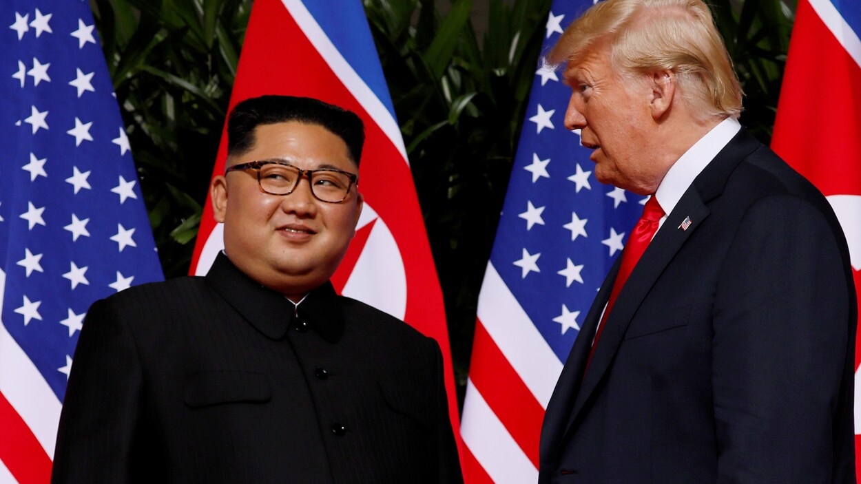 Kim Jong-un sourit en regardant au loin, à côté de Donald Trump.
