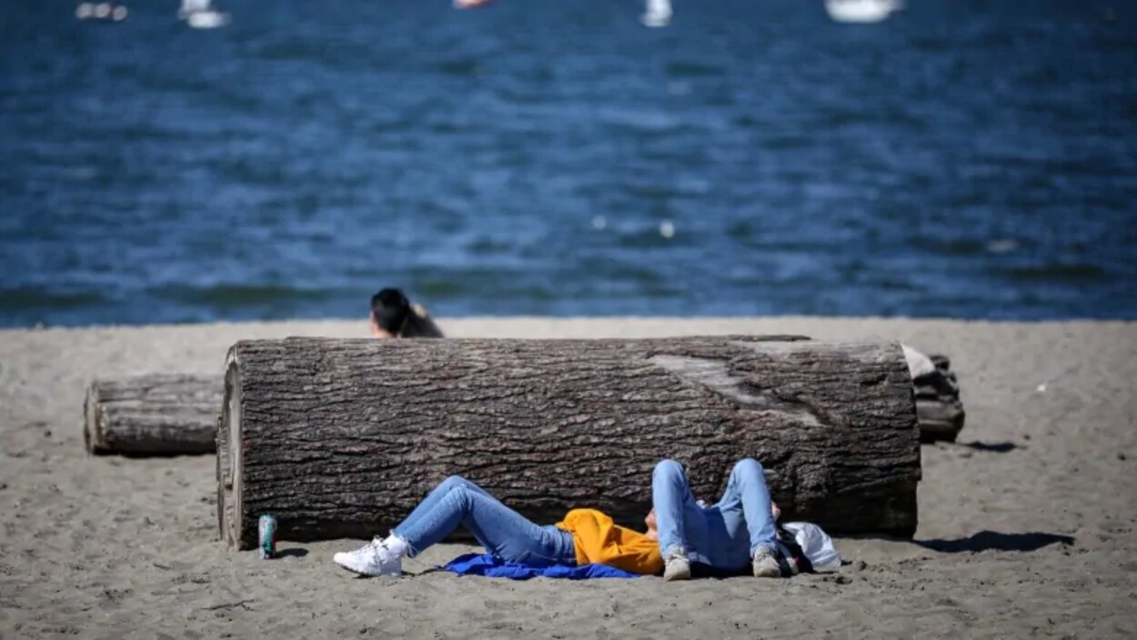 Des gens se prélassent au soleil sur une plage de Vancouver.