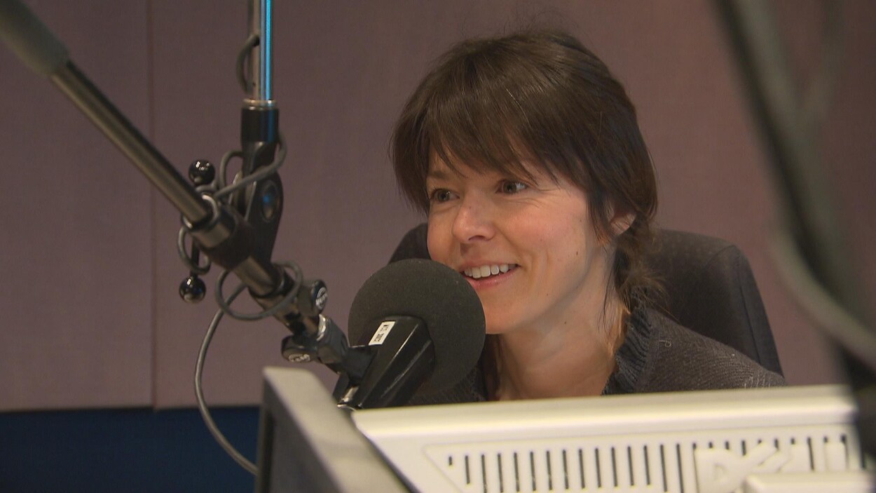 Une femme souriante est assise dans un studio de radio derrière un micro. Une femme souriante est assise dans un studio de radio derrière un micro.