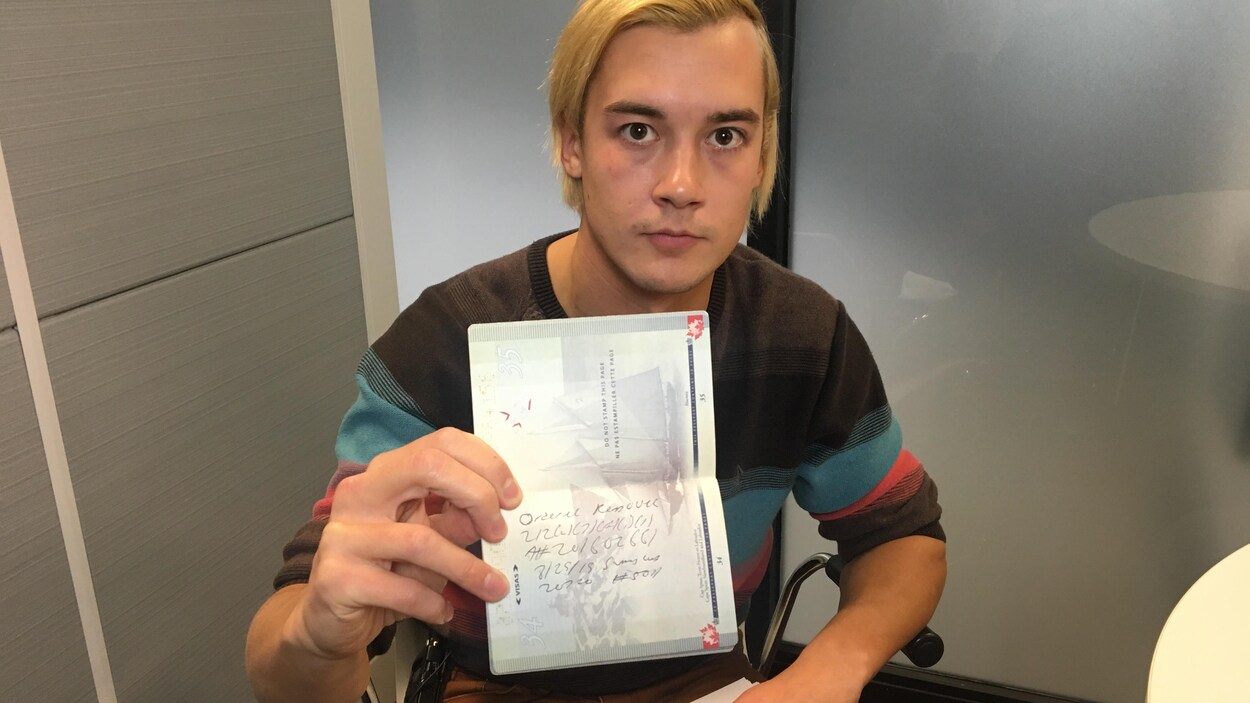 Kyle Kuchirka tient dans sa main un passeport dans lequel est écrit une note.