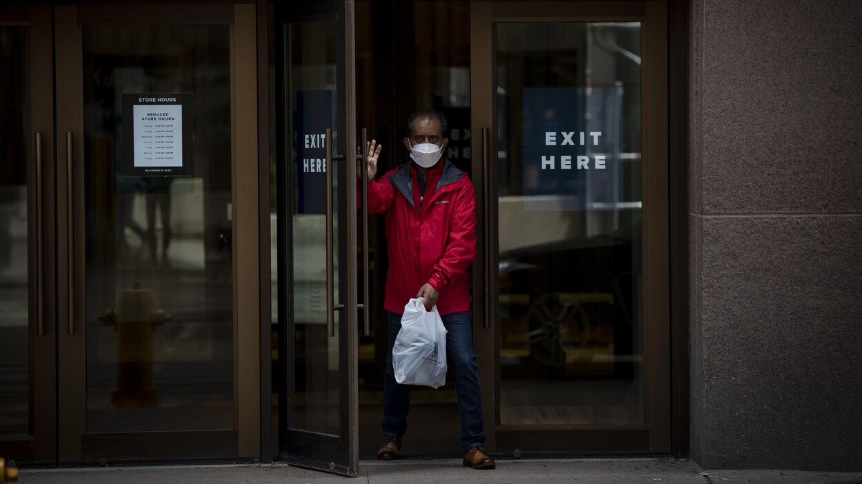 Un homme qui porte un masque sort du grand magasin La Baie au centre-ville de Toronto.