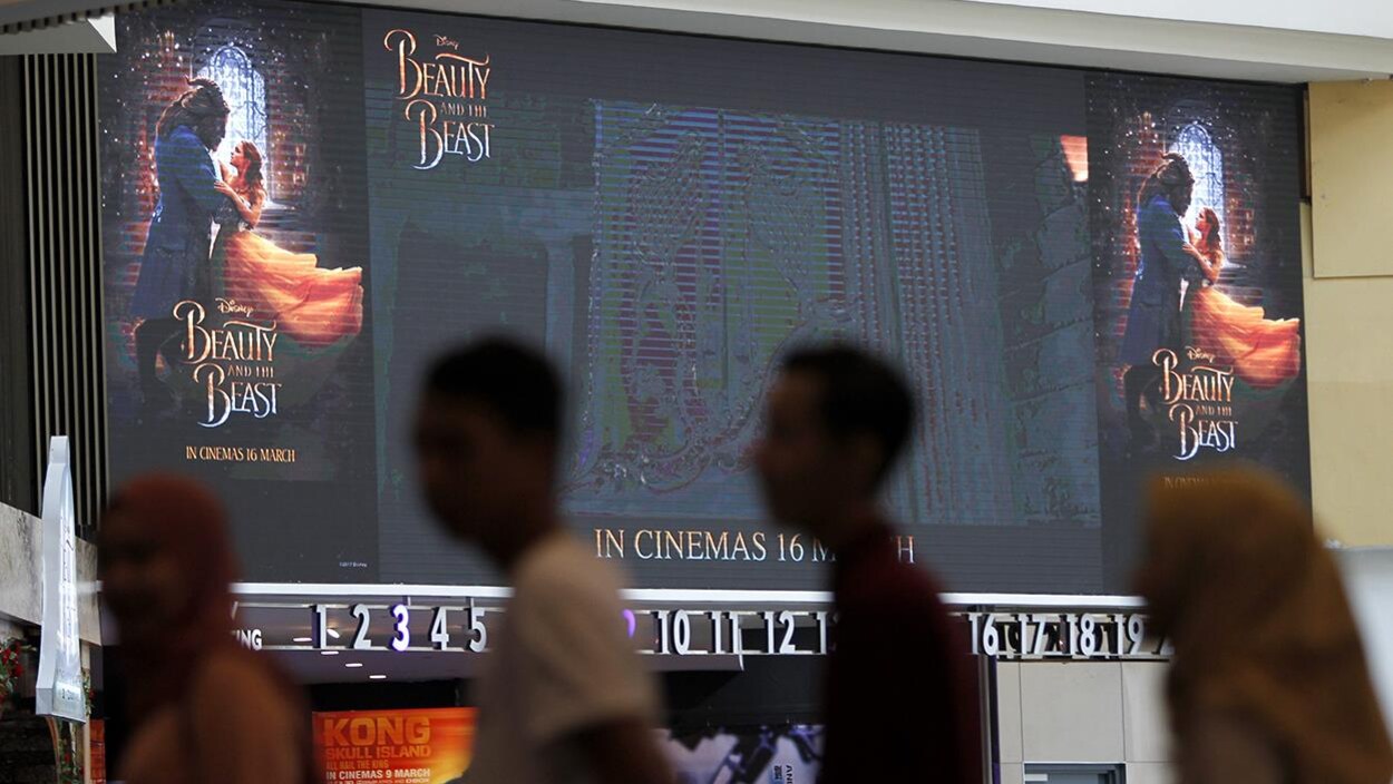 Des cinéphiles font la file dans un cinéma qui contient une affiche de « La Belle et la Bête », à Kuala Lumpur en Malaisie Des cinéphiles font la file dans un cinéma qui contient une affiche de « La Belle et la Bête », à Kuala Lumpur en Malaisie