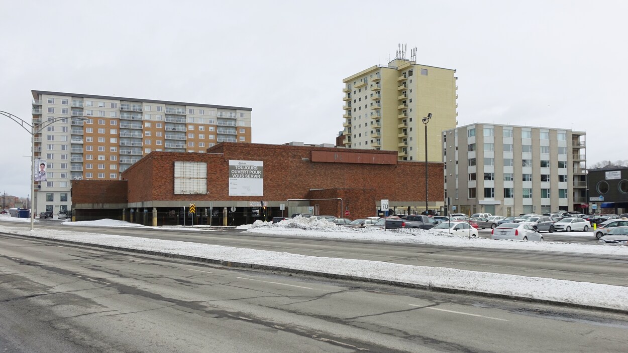 L'édifice de la Grande Place près d'un stationnement et d'autres immeubles du centre-ville de Rimouski.