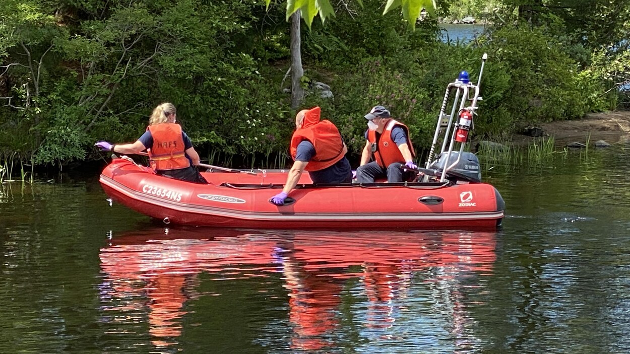 Trois personnes dans un bateau sur un lac.