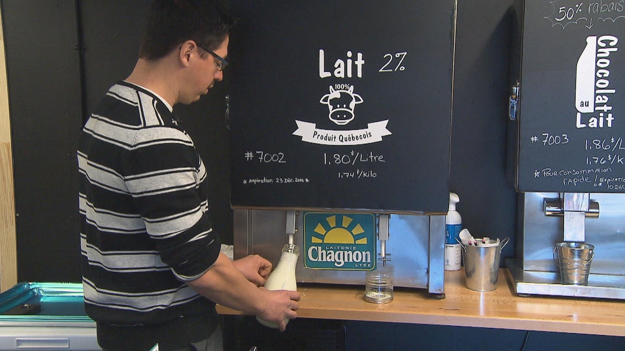 Un homme rempli une bouteille de verre avec du lait en fut.
