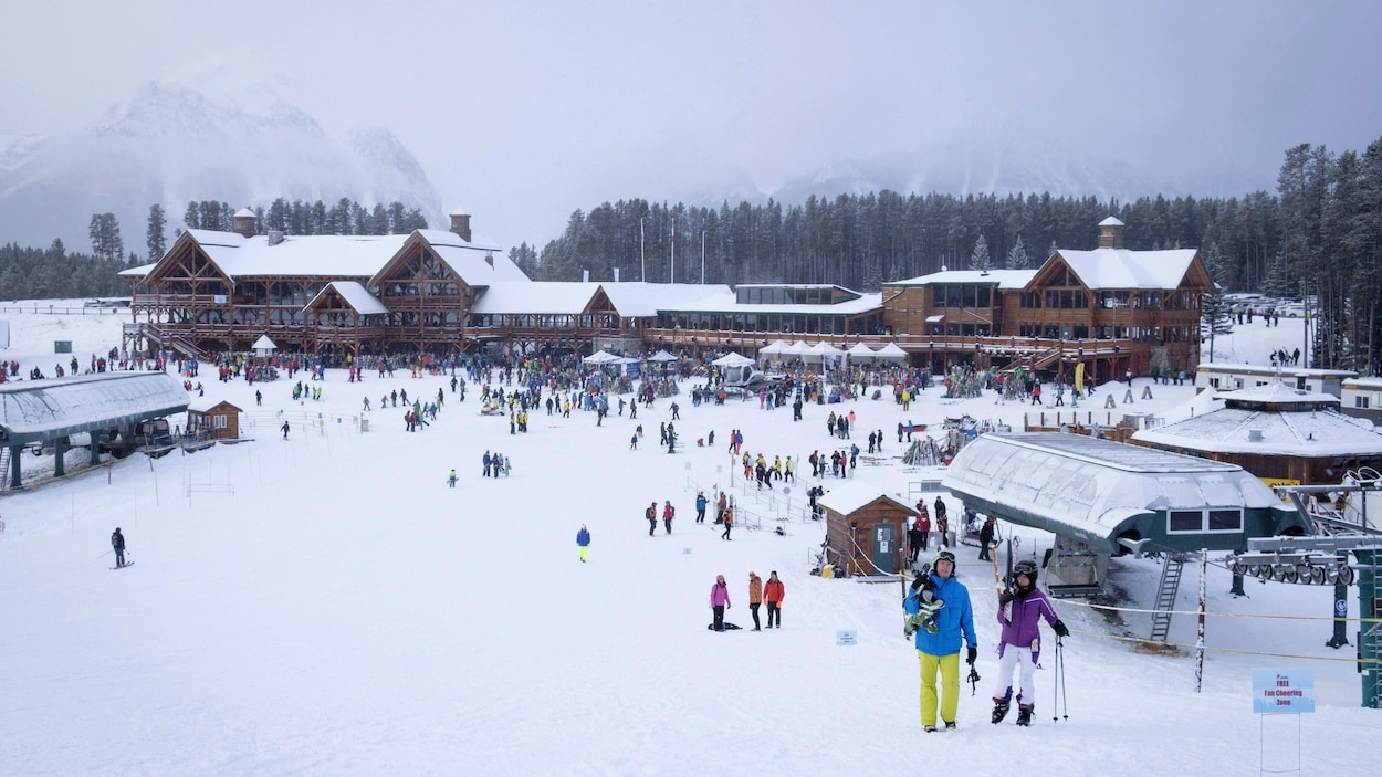L'endroit central de la station de sports d'hiver, avec les montagnes au loin, rempli de skieurs s'y rassemblant.