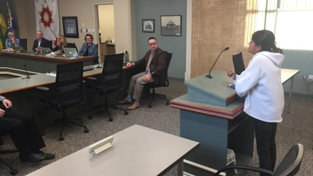 Laraib Ahmed, debout derrière un pupitre, prend la parole devant les membres du conseil d’administration de la Division scolaire publique de Saskatoon.