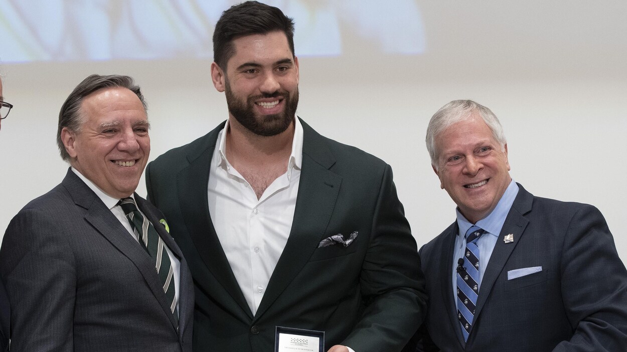 Deux élus entourent Laurent Duvernay-Tardif, qui a reçu la Médaille d'honneur de l'Assemblée nationale.