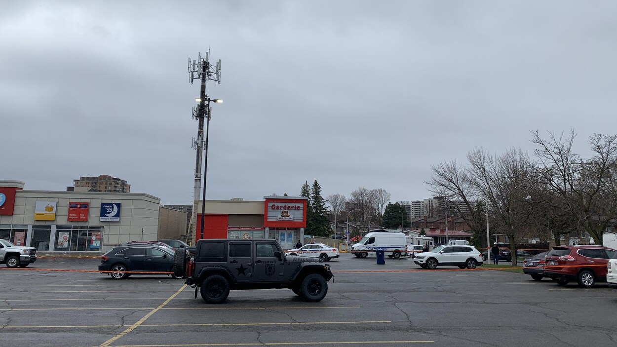 Une tour de communication dans un stationnement de centre commercial entourée de voitures et de policiers à la suite d'un incendie.