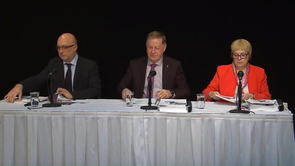 Les trois personnes s'adressent à la presse.