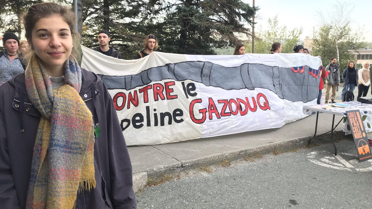 La porte-parole de La planète s'invite à l'université, Léa Ilardo devant une banderole sur laquelle est inscrit « Contre le pipeline gazoduq ».