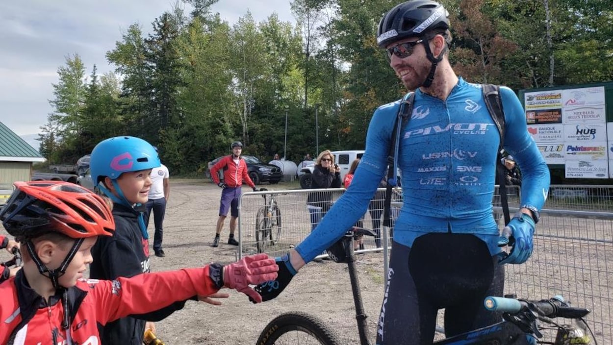 De petits cyclistes encouragent l'athlète Léandre Bouchard.
