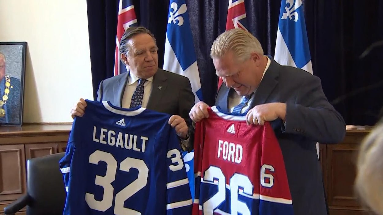 Deux chandails de hockey tenus dans les mains de deux politiciens.
