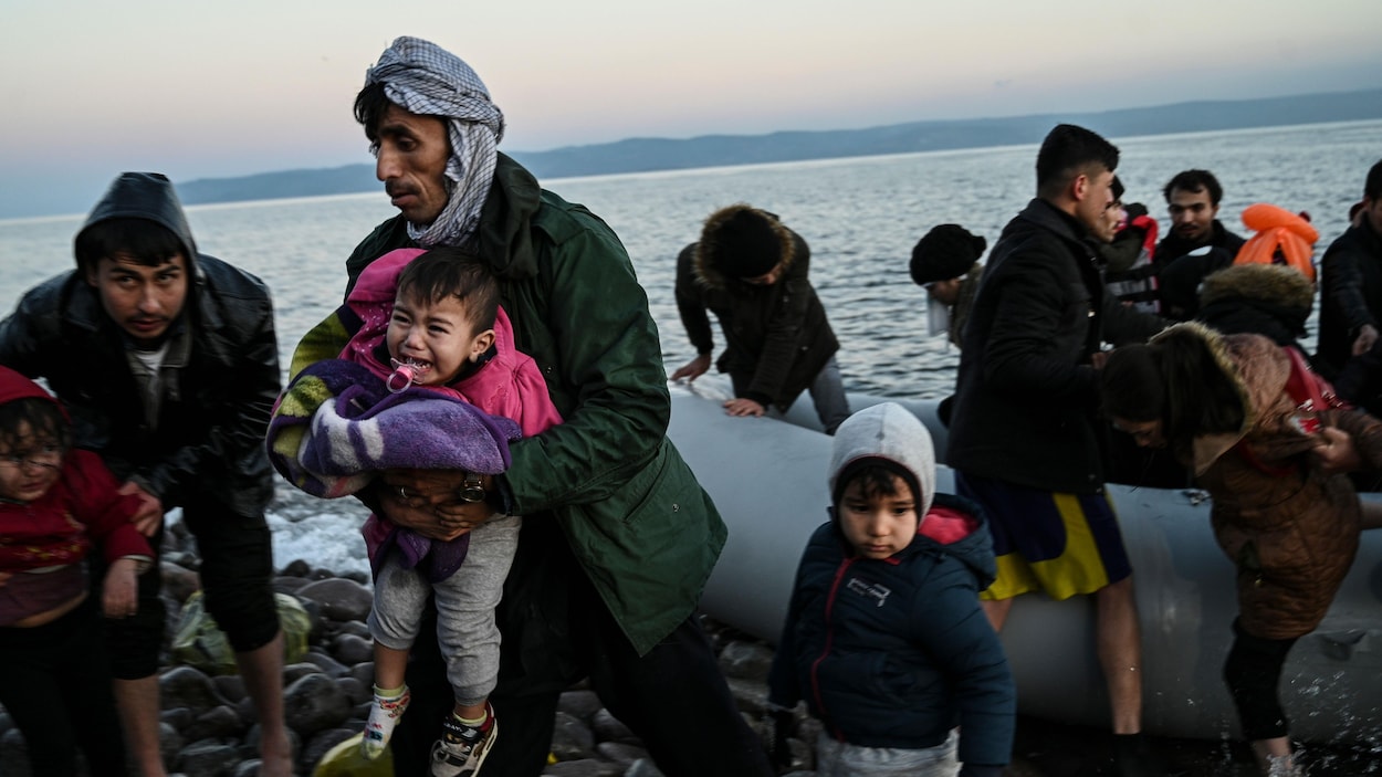 Des parents avec leurs enfants débarquent d'un canot pneumatique sur les berges d'un île.