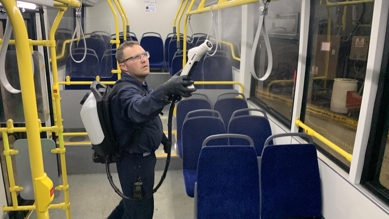 Un homme nettoie des sangles dans un autobus.