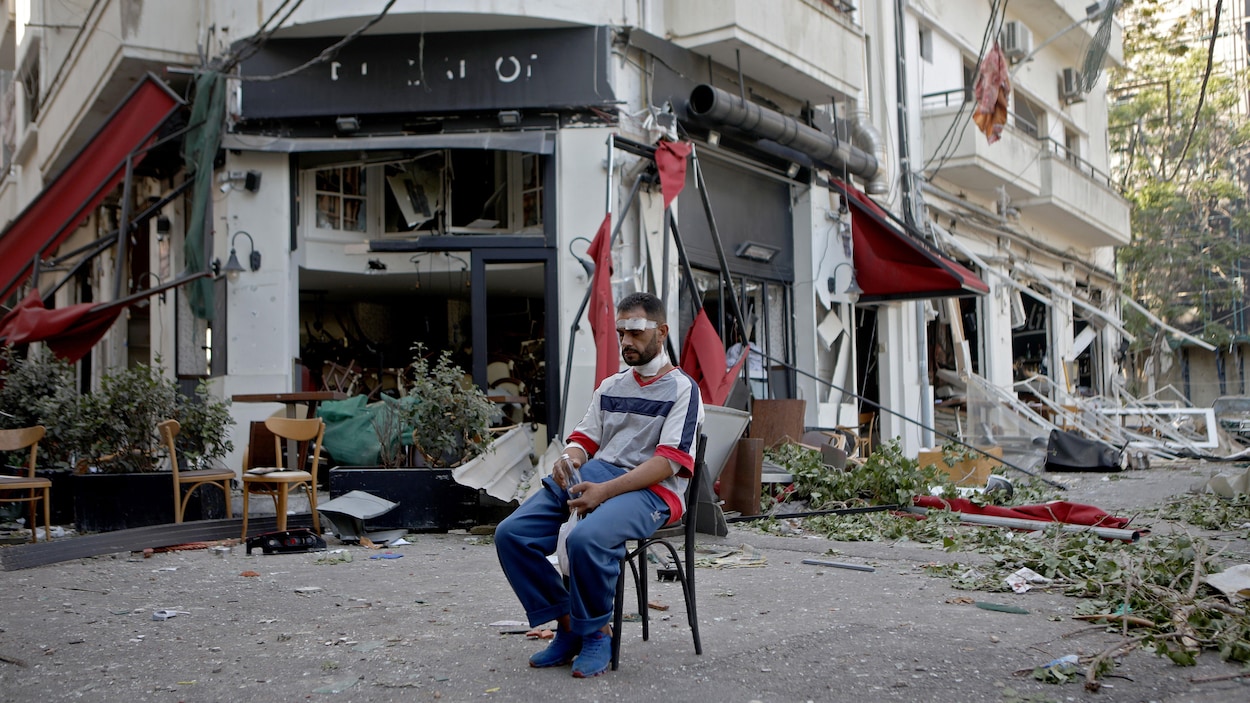 Un homme blessé est assis à côté d'un restaurant dans le quartier de Mar Mikhael à Beyrouth au lendemain de l’explosion.