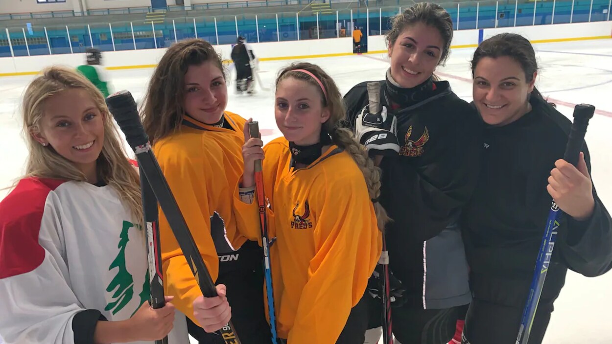 Des joueuses de hockey posent sur une patinoire.