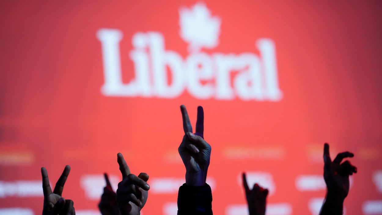 Des partisans libéraux font le signe de la victoire lors d’un rassemblement le soir des élections.