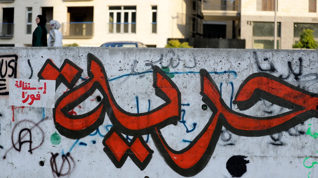 Un graffiti représentant une calligraphie arabe peinte en rouge et noir.