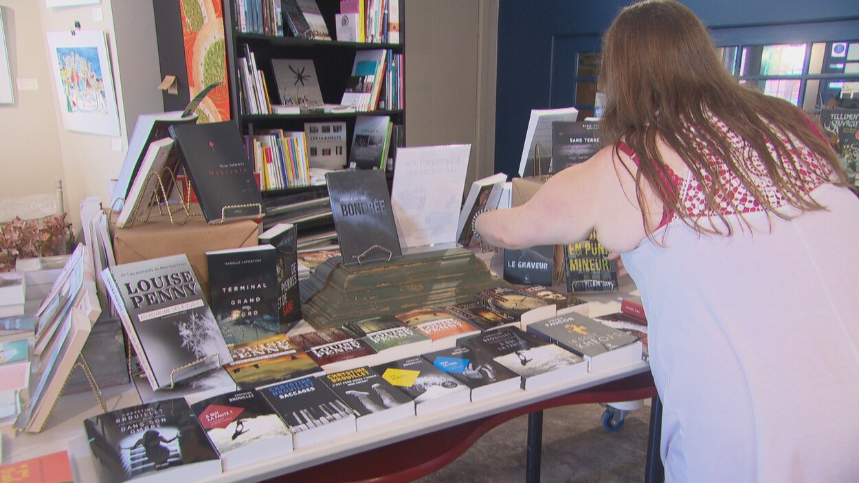 Une femmes place des livres sur une table dans une librairie.