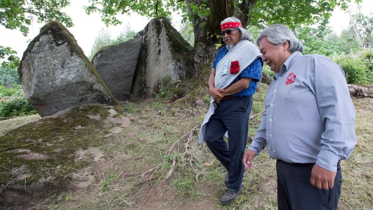 Le chef Dalton Silver et Sonny McHalsie marchent l'un à côté de l'autre autour de deux gros rochers.