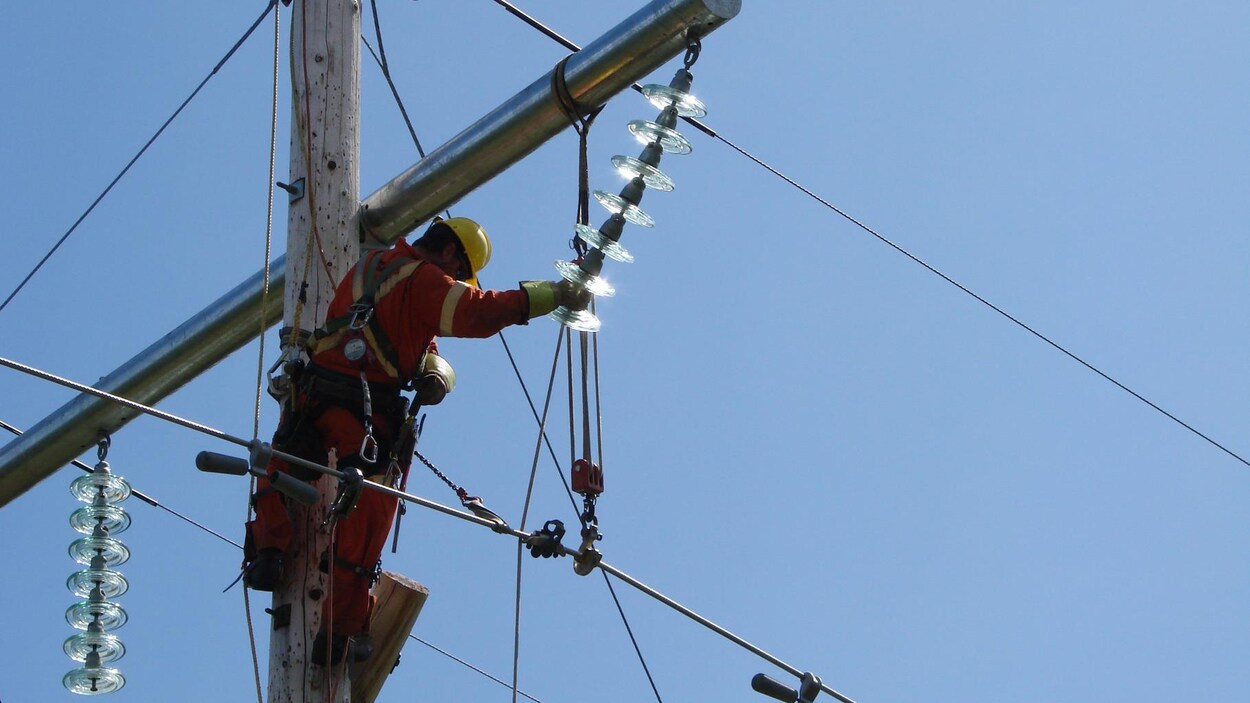 Un monteur de structures d'acier travaille sur une ligne électrique.
