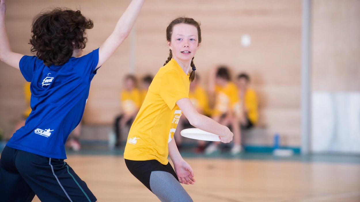 Une jeune fille lance un frisbee, un garçon tentant de la bloquer.