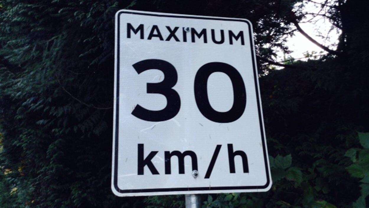 Un panneau routier indique une vitesse maximale de 30 km/h autorisée.