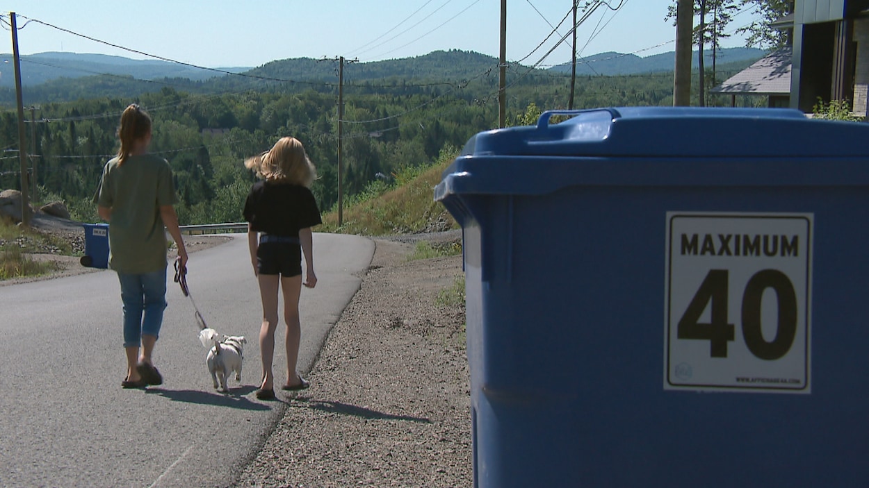 Deux jeunes filles circulent à pied dans une rue de Stoneham à proximité d'un bac de recyclage sur lequel se trouve un autocollant indiquant une vitesse maximale de 40 km/h.