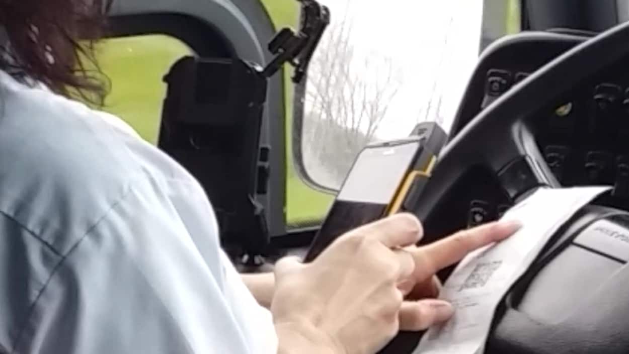 Une employée de Limocar manipule un lecteur optique en conduisant. Une employée de Limocar manipule un lecteur optique en conduisant.