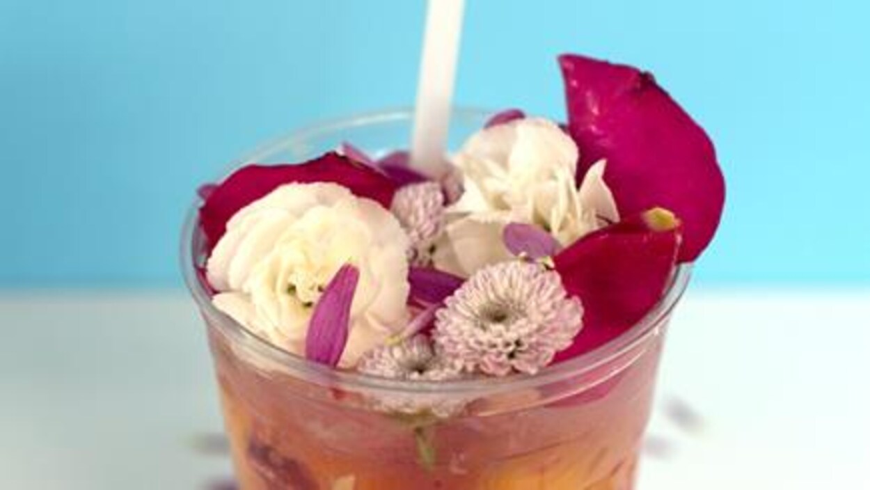 Une limonade avec des fleurs comestibles dans un verre en plastique.