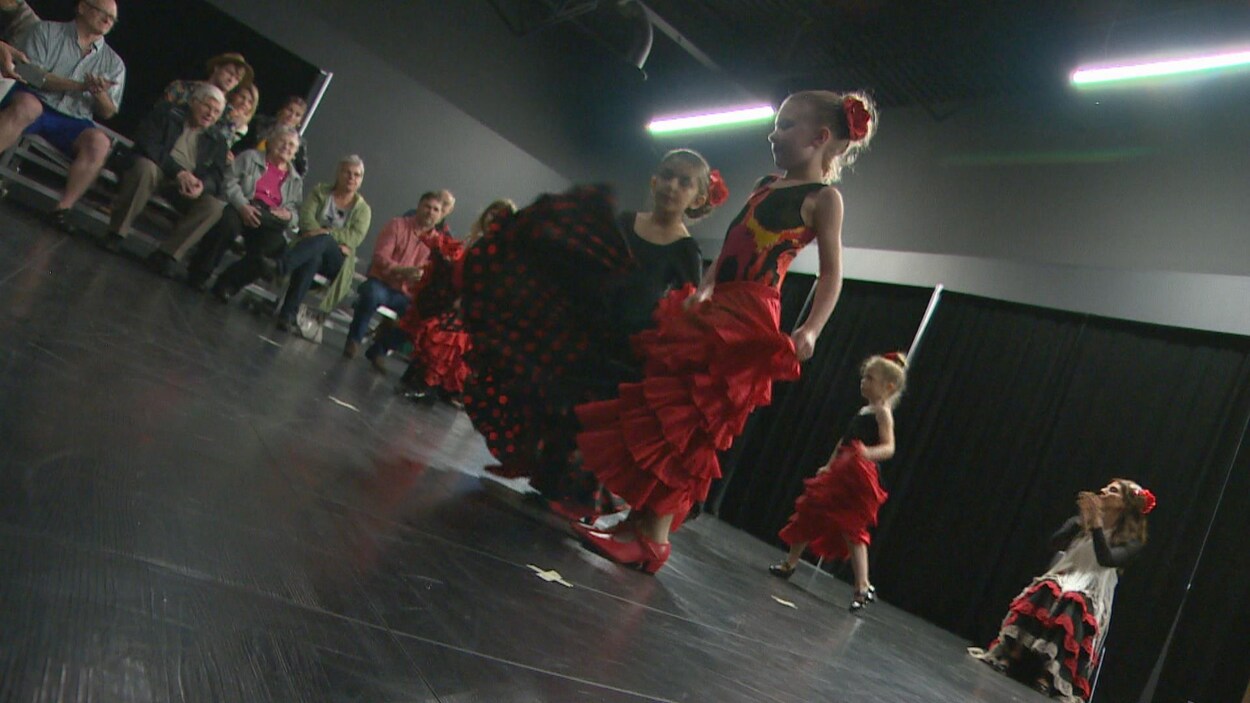 Des jeunes dansent du flamenco en avant-plan. Lina Kazan applaudit de façon rythmique en arrière-plan.