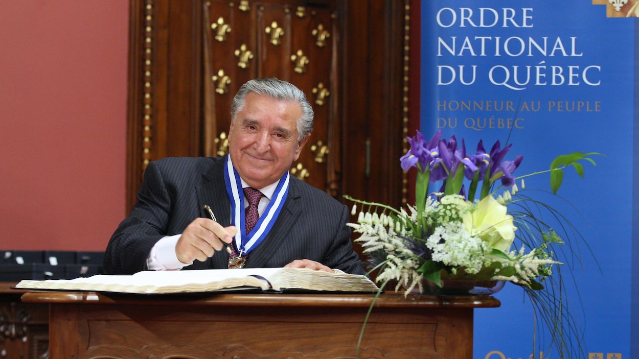 Lino Saputo signe un registre officiel lors de la remise de l'Ordre national du Québec.