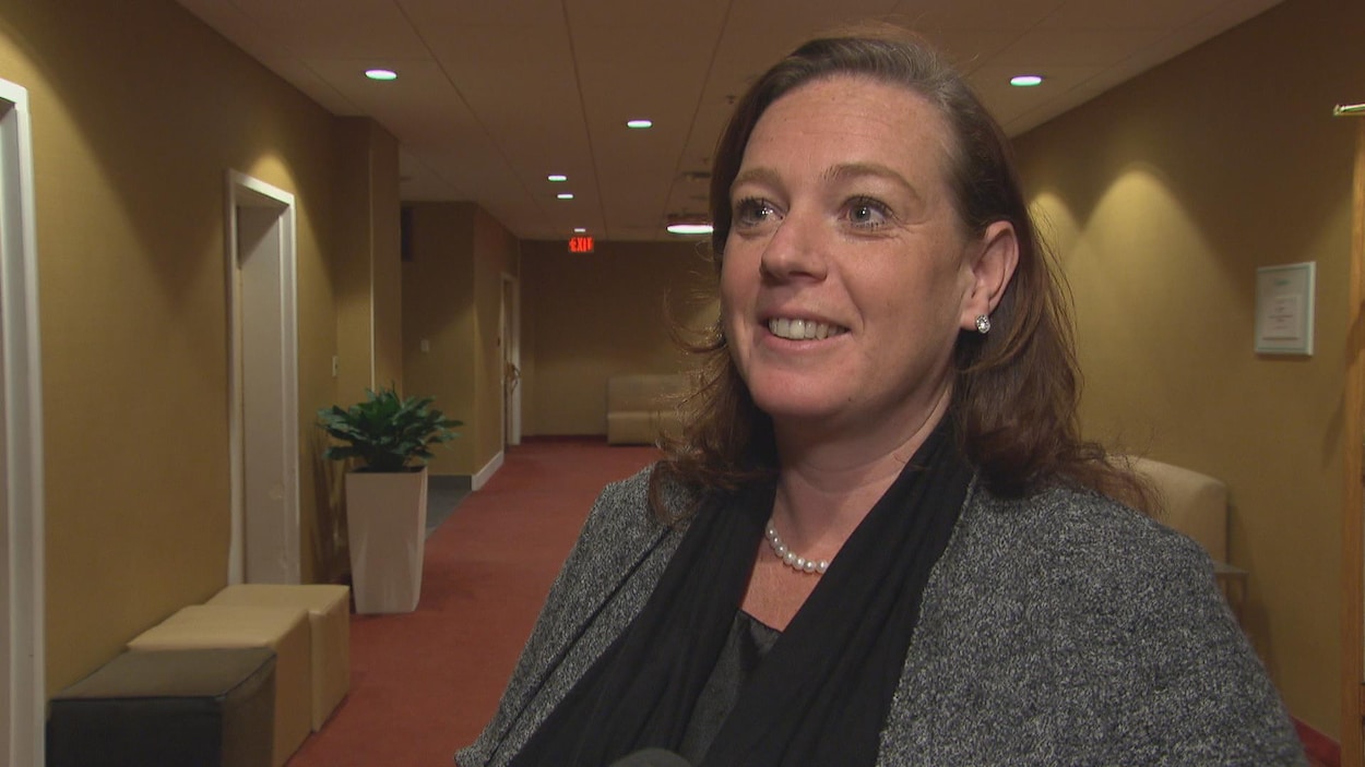 La députée est debout dans un corridor et fait face à la caméro