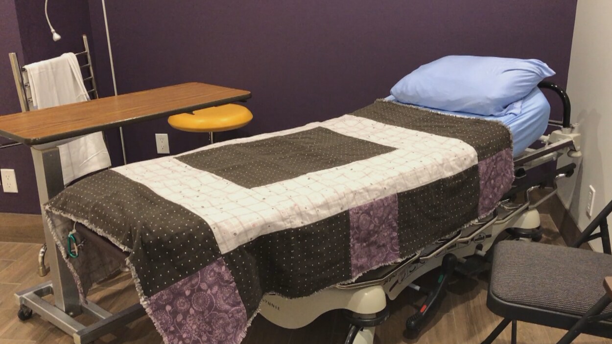 Un lit d'hôpital est recouvert d'un drap multicolore.