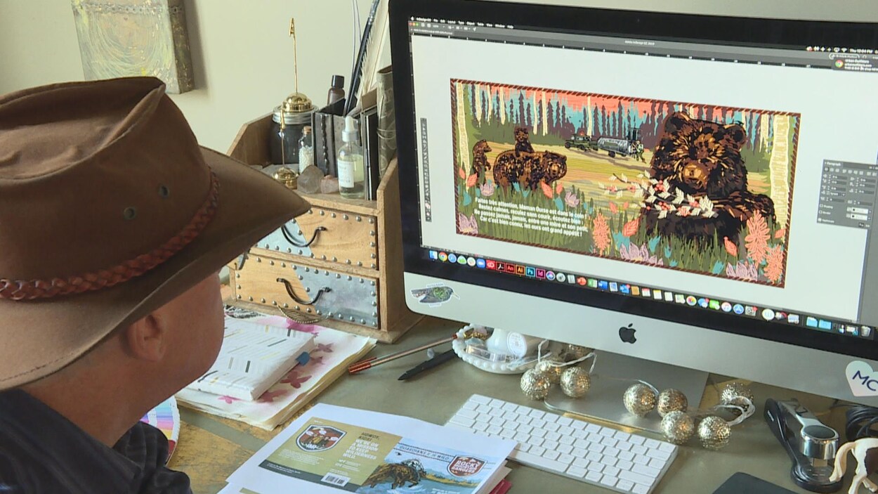 Un homme est assis, de dos, devant un bureau avec un écran d'ordinateur dessus.
Il porte un chapeau cowboy. L'écran montre une illustration colorée d'ours.