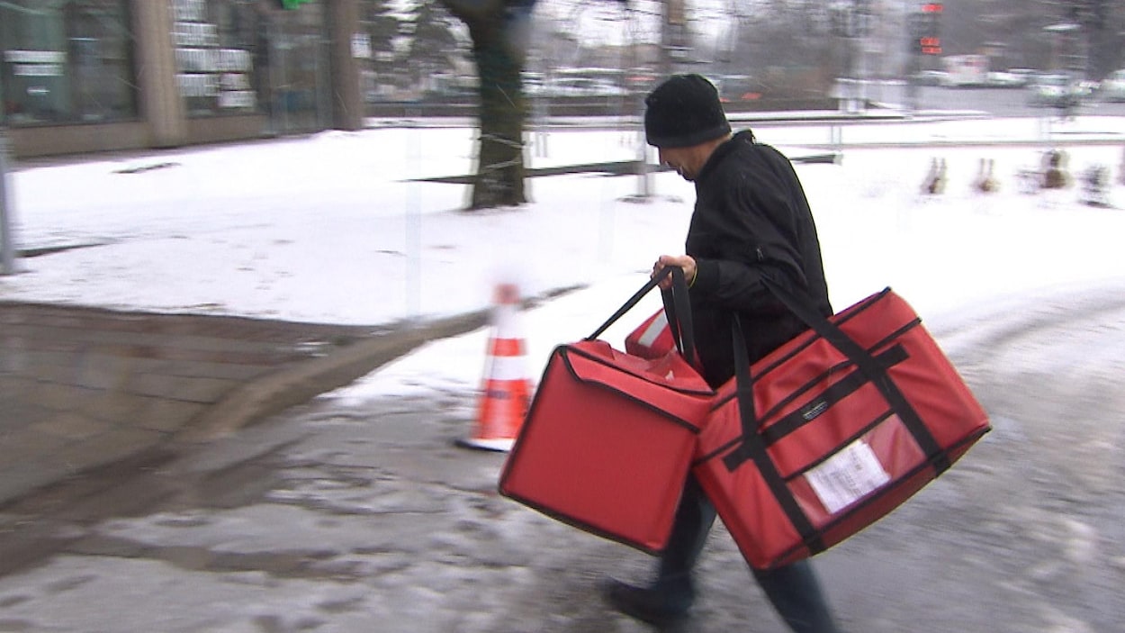 Un livreur porte plusieurs sacs.