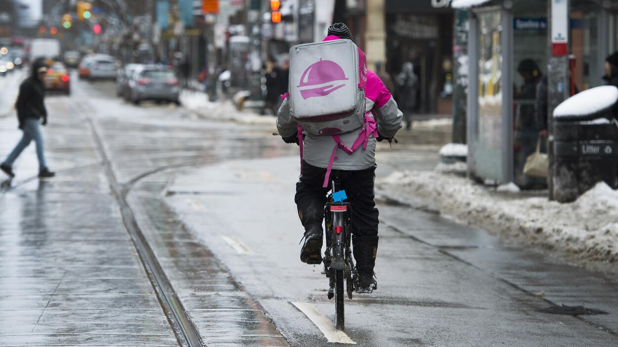Un homme qui porte un gros sac à dos roule à vélo.