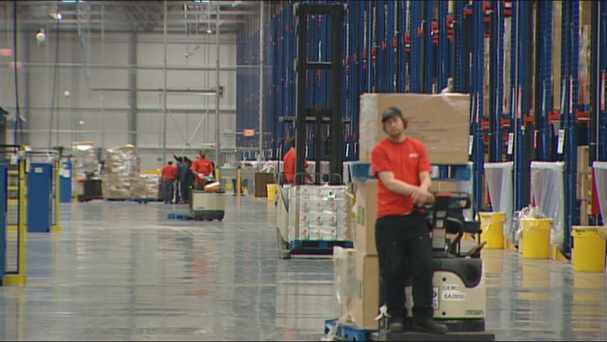 Un entrepôt où des personnes travaillent en déplaçant des cartons.