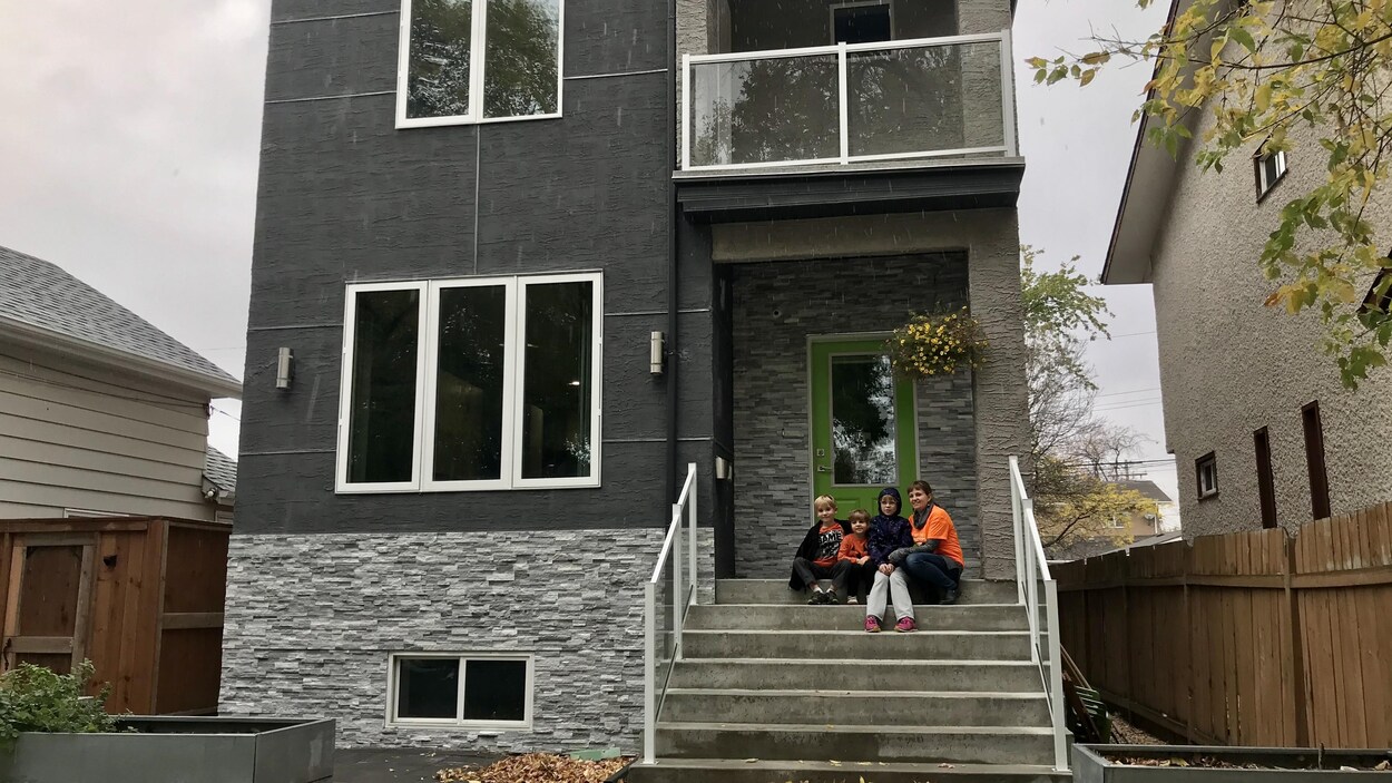 Roxanne Breton et ses trois enfants se trouvent sur le perron d'une maison intercalaire, plus haute que les bâtiments voisins.