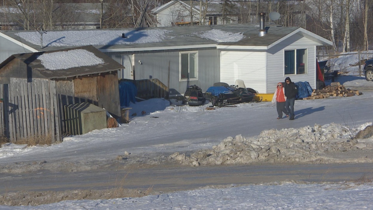 Deux personnes marchent dans une ruelle enneigée de la communauté de Southend, dans le nord de la Saskatchewan. Deux personnes marchent dans une ruelle enneigée de la communauté de Southend, dans le nord de la Saskatchewan.