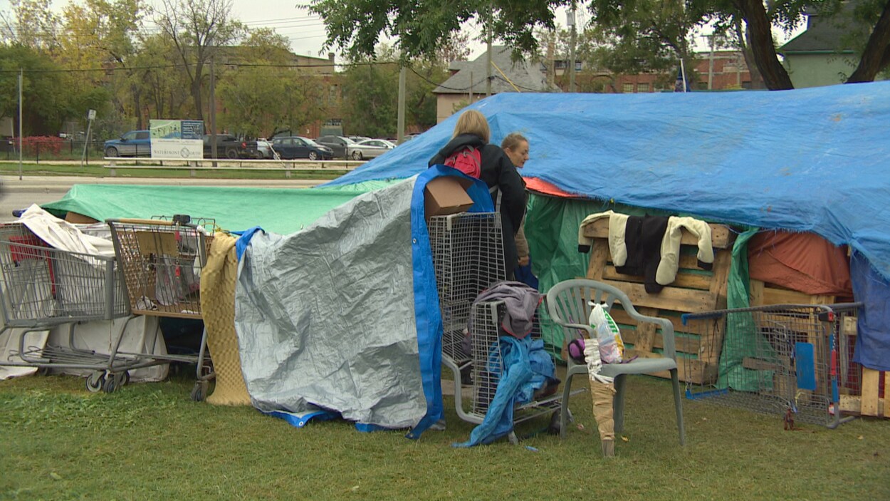 Deux femmes devant une tente dans un campement de sans-abri.