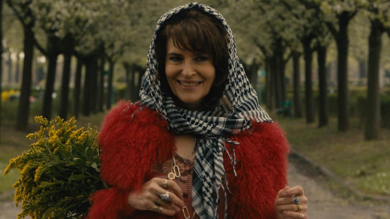 Fanny Ardant marche dans un parc et sourit dans le film Lola Pater . Fanny Ardant marche dans un parc et sourit dans le film Lola Pater .