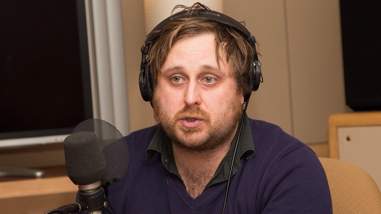 Pierre Guy Blanchard derrière un micro lors d'un enregistrement radio.