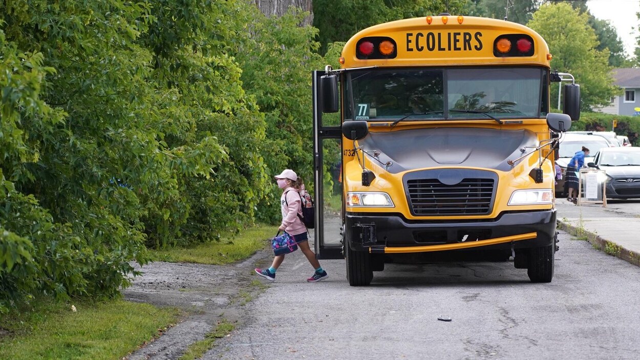 La jeune fille masquée descend de l'autobus scolaire.