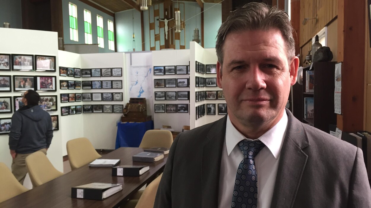 Louis Pelletier pose pour la caméra dans une église aménagée pour une rencontre.